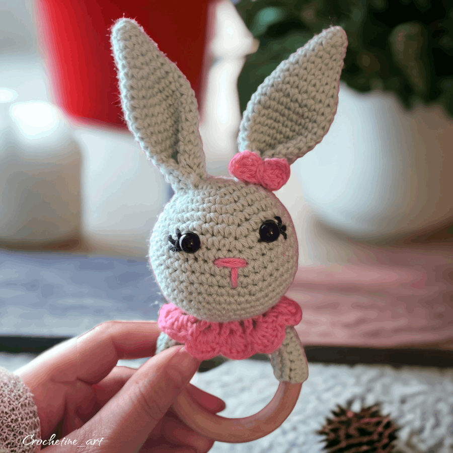 Hochet lapin de couleur vert d'eau et rose au crochet artisanal en fil coton. avec anneau de dentition en bois naturel