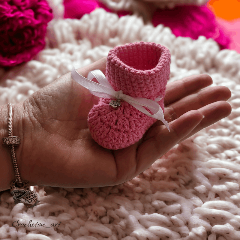 Chausson de naissance au crochet artisanal en fil coton rose agrémentés d'un ruban de serrage et petite breloque