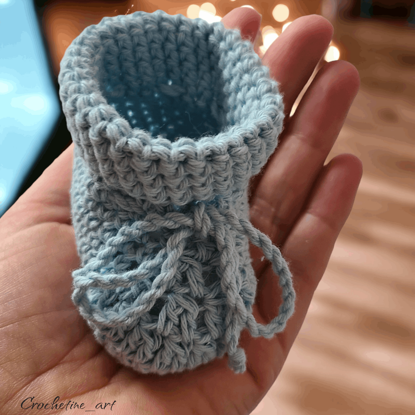 Coffret cadeau de naissance pour bébé au crochet comprenant un hochet, une paire de chausson taille 0 à 3 mois, une dragonne pour tétine ourson réalisée au crochet avec fil coton bleu et perle de bois