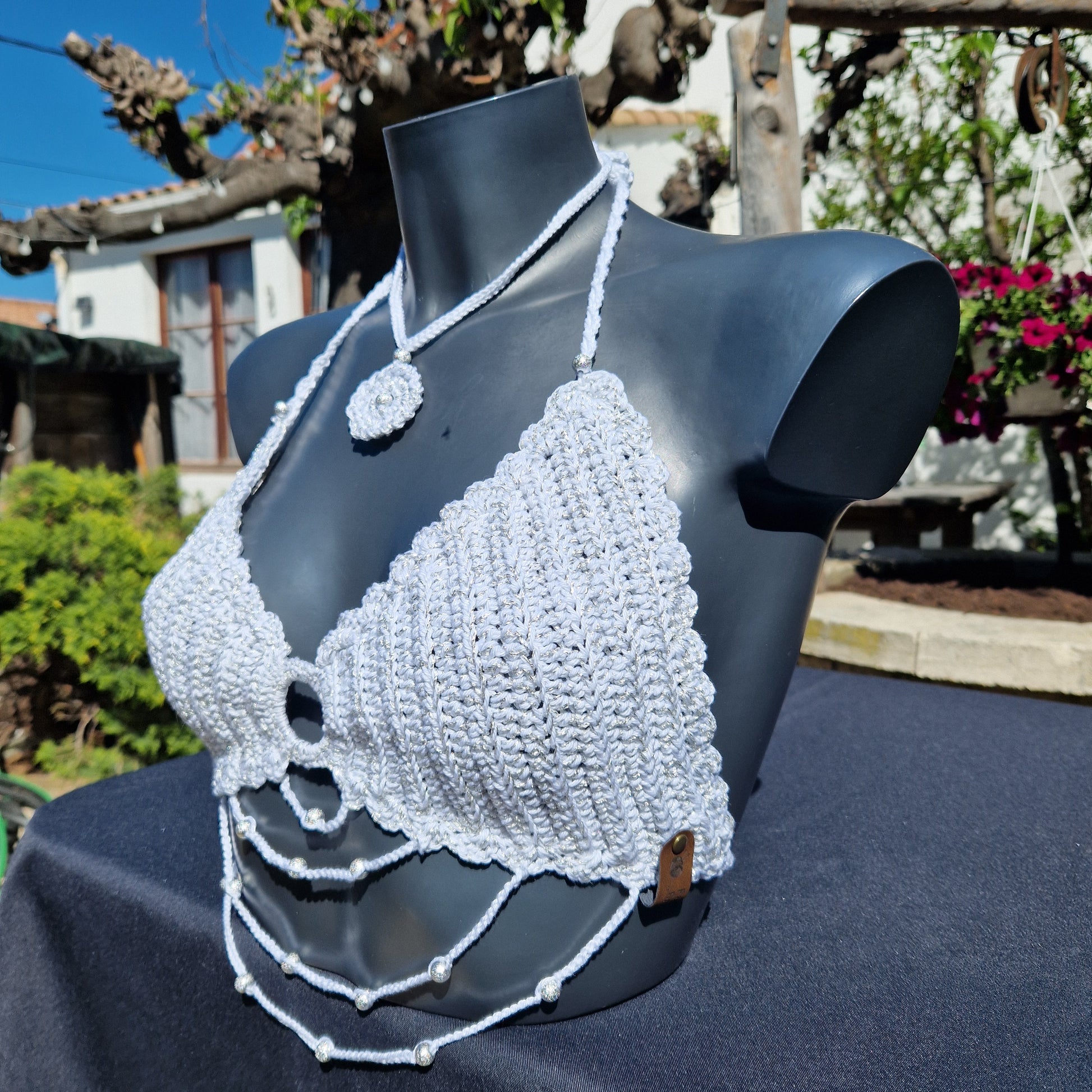 Haut crop top fait main au crochet de couleur blanc et argenté orné de perles argentées.