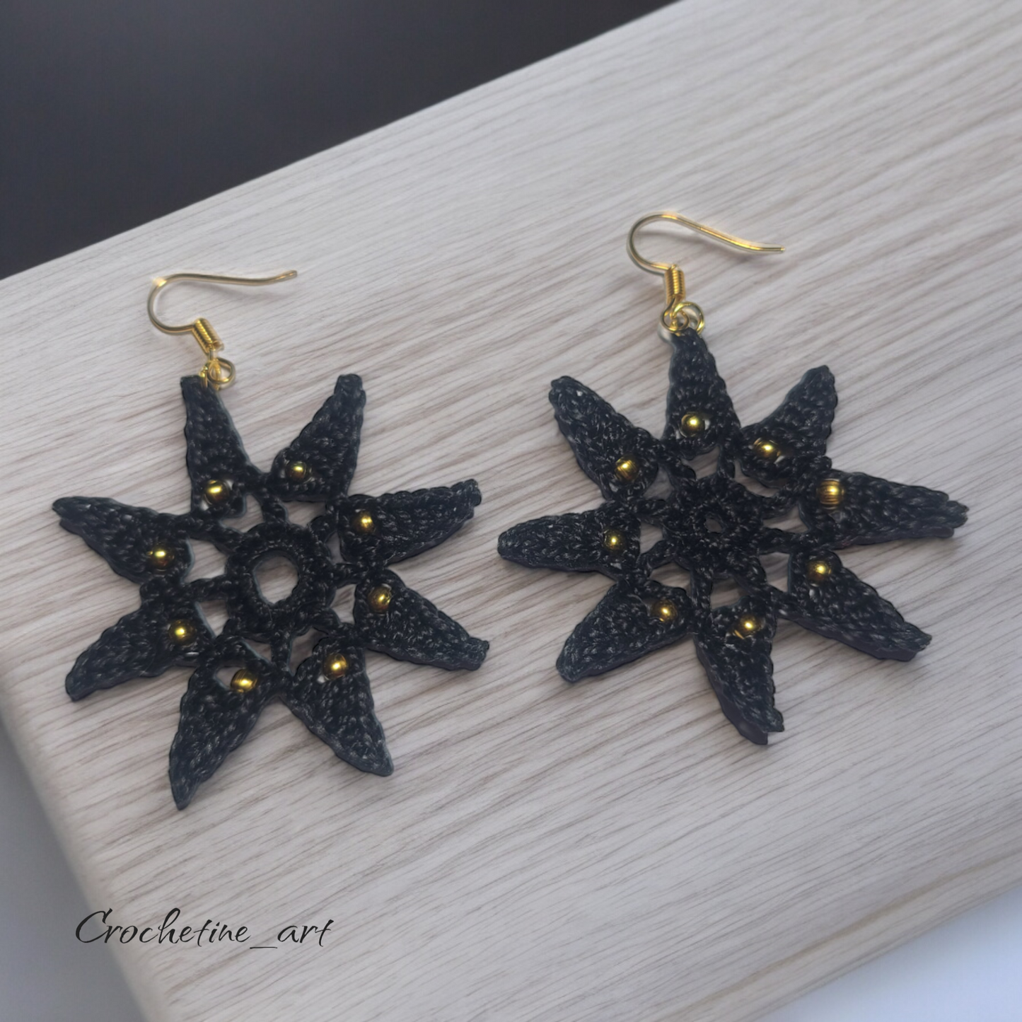 Boucles d'oreilles étoile Véga au crochet de couleur noire avec perles dorées.