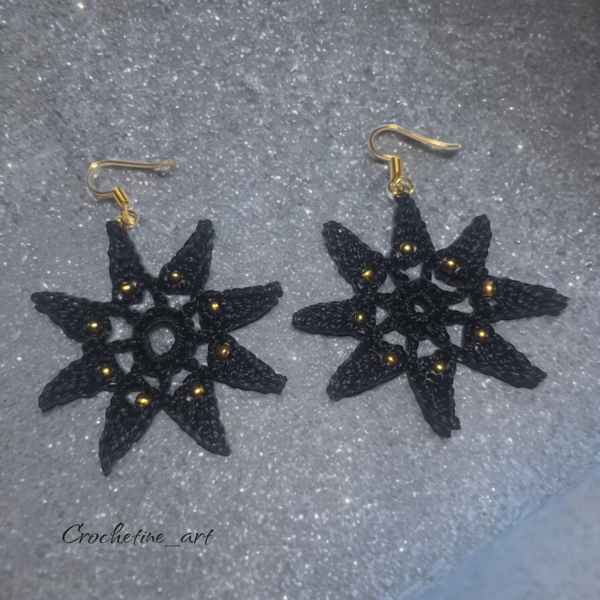 Boucles d'oreilles étoile Véga au crochet de couleur noire avec perles dorées.